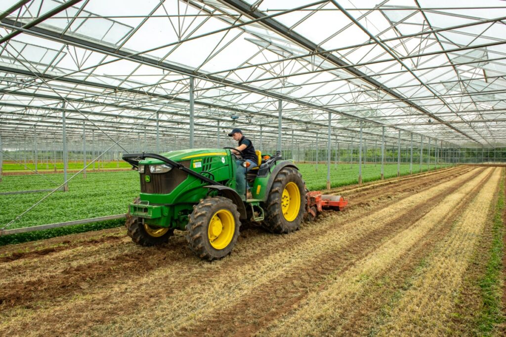 a person driving a tractor in a greenhouse